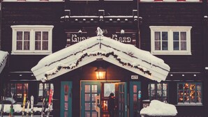 Un bâtiment dont l’entrée est recouverte de neige et au-dessus de la porte, on peut voir une cloche.