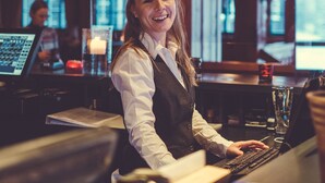 Un espace bar avec un barman derrière le comptoir, un plafond en bois et des tabourets de bar.