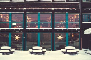 Un edificio con ventanas amplias y mobiliario exterior cubierto de nieve.
