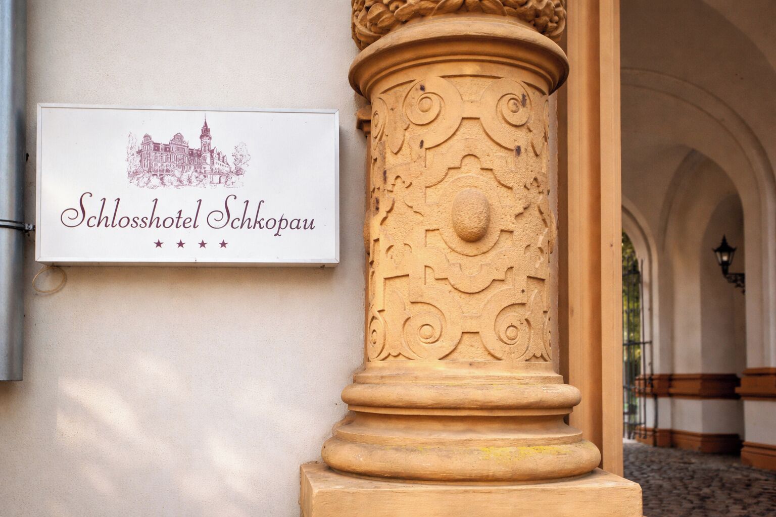 Une enseigne pour l’hôtel « Schlosshotel Schkopau », avec une illustration du bâtiment et une colonne décorative.