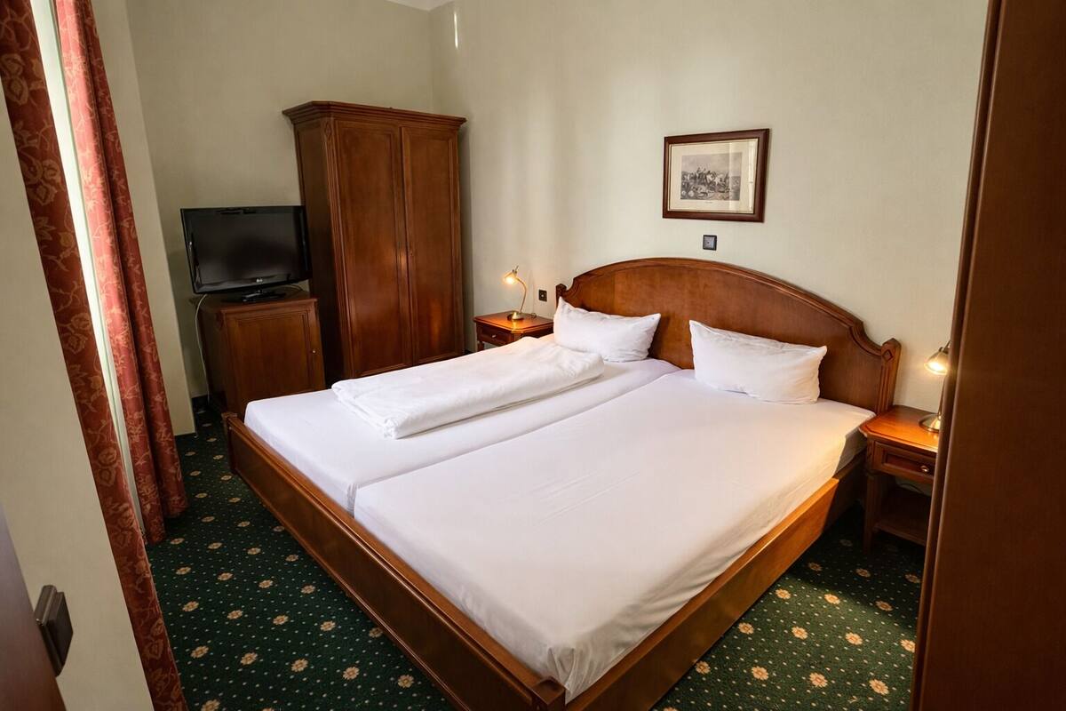 Habitación de hotel con cama doble, televisión, armario y un cuadro en la pared.