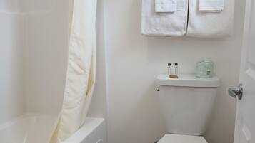 A bathroom with a bathtub, toilet, and a shower curtain.