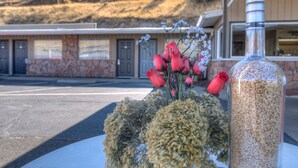 A table with a bouquet of flowers and a bottle of grains. - Three Rivers Inn (Biggs Junction)
