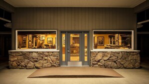 A building with a stone facade, a central door, and two large windows displaying interior spaces. - Three Rivers Inn (Biggs Junction)