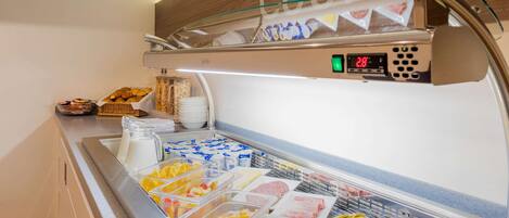 A self-service breakfast buffet with various food items and a digital clock displaying the time.