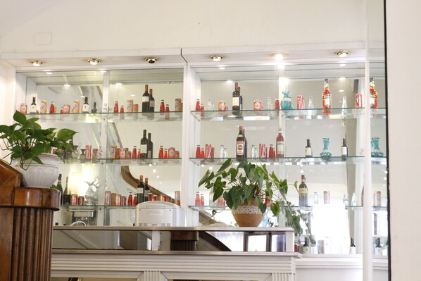 A bar area with multiple shelves displaying various bottles and glasses. - Hotel San Giusto (Rome)