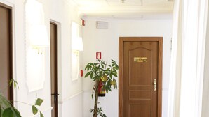 En hotelgang med en trædør med påskriften "DIRECTIONS", en potteplante og et marmorgulv.