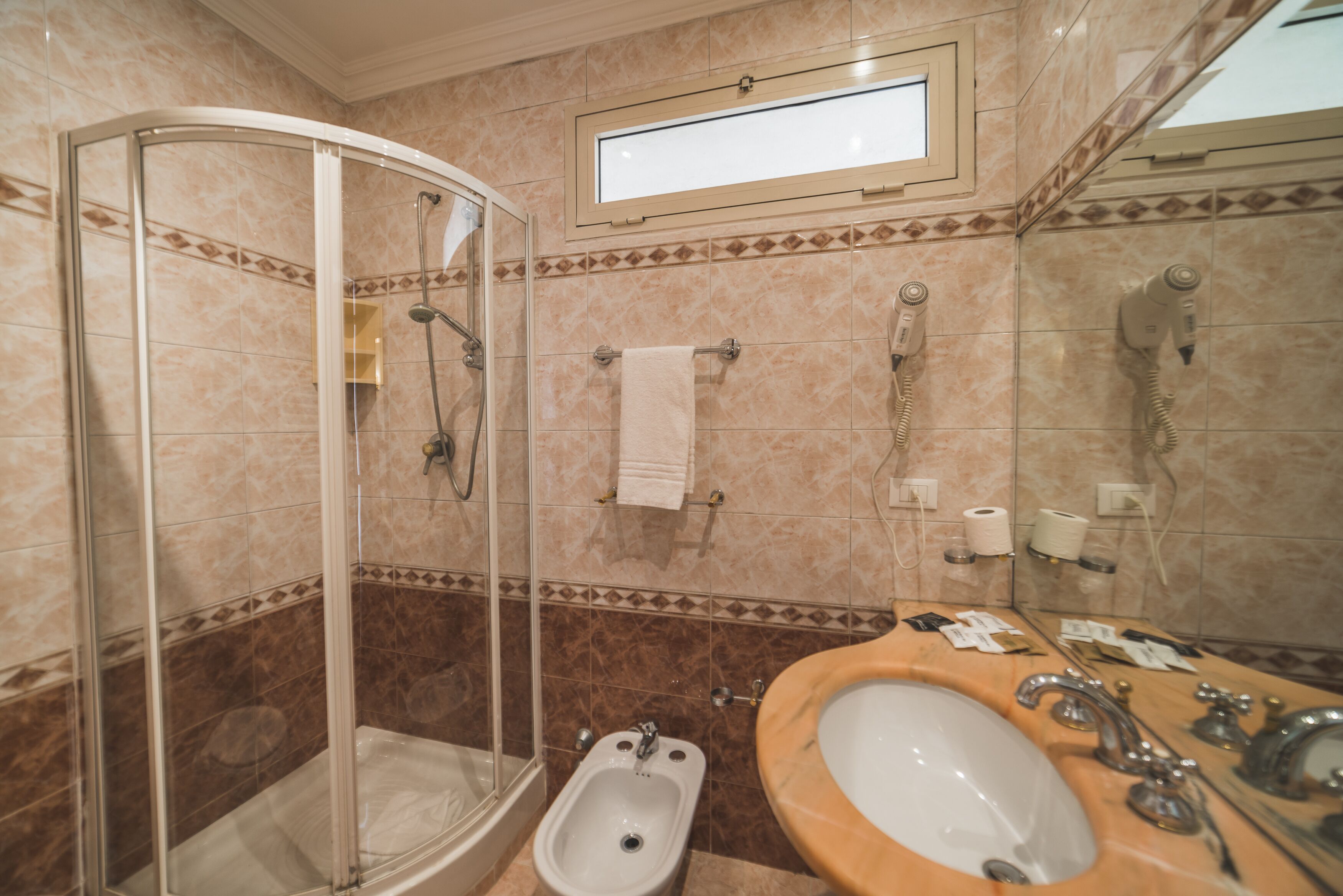 Ein Badezimmer mit Duschkabine, Waschbecken mit Spiegel und Handtuchhalter.