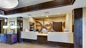 A reception area with a large mural of a bridge, a reception desk, and a counter. - Staybridge Suites San Angelo by IHG (San Angelo)