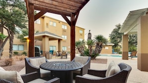 An outdoor patio area with wicker furniture, a round table, and a pergola structure. - Staybridge Suites San Angelo by IHG (San Angelo)