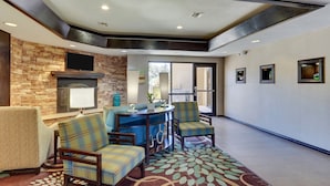 A modern lobby with a stone wall, a fireplace, a bar area, and seating. - Staybridge Suites San Angelo by IHG (San Angelo)