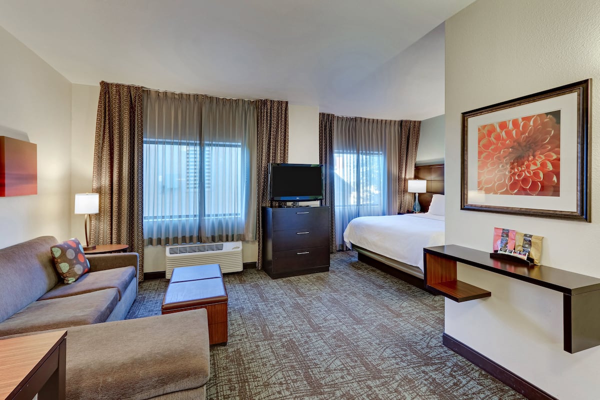 A hotel room with a bed, a desk, a TV, a sofa, and a coffee table.