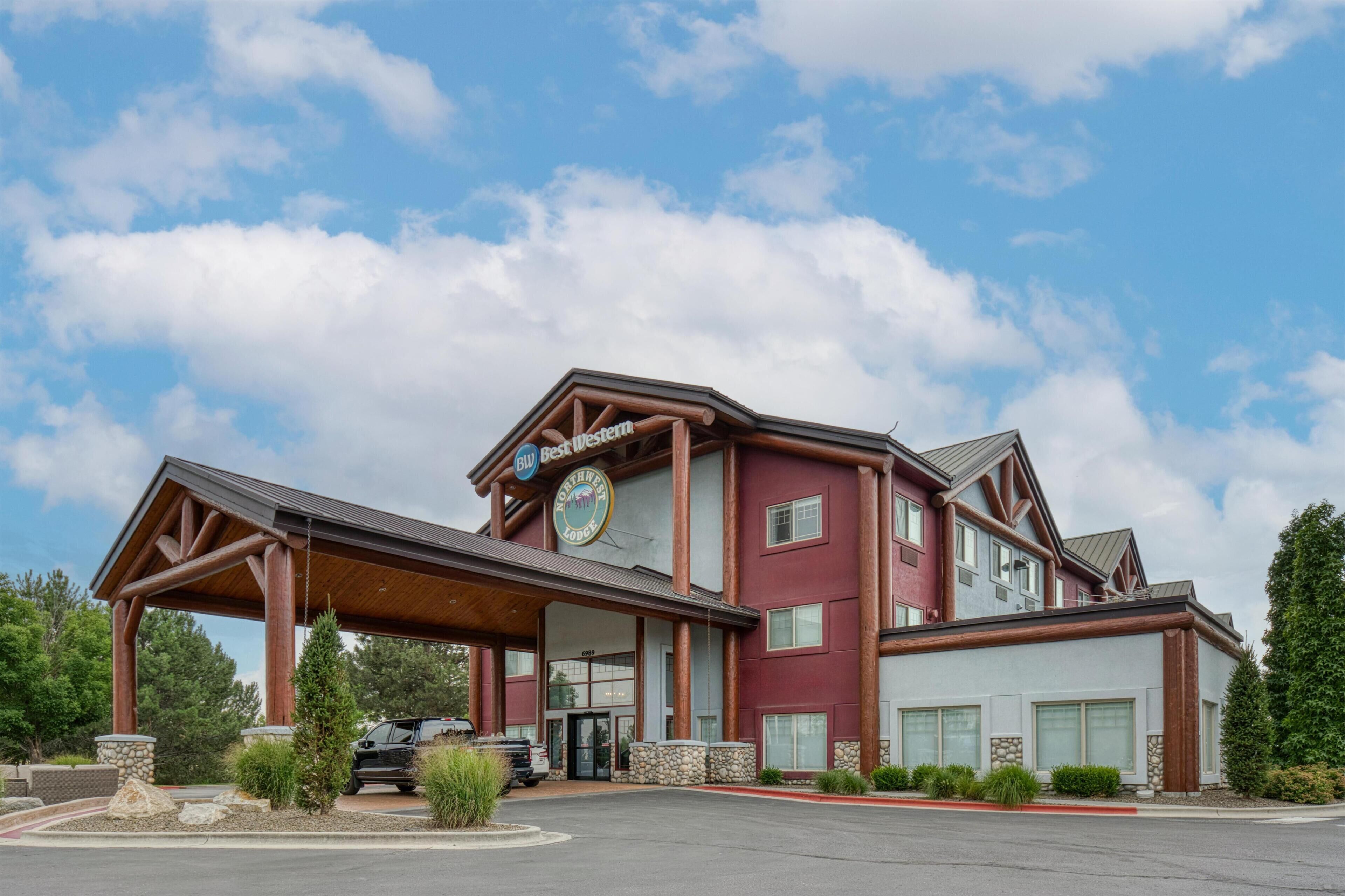 Een meerhoog hotel met een opvallend ‘Best Western’ bord, een overdekte ingang en een parkeerplaats met verschillende voertuigen.