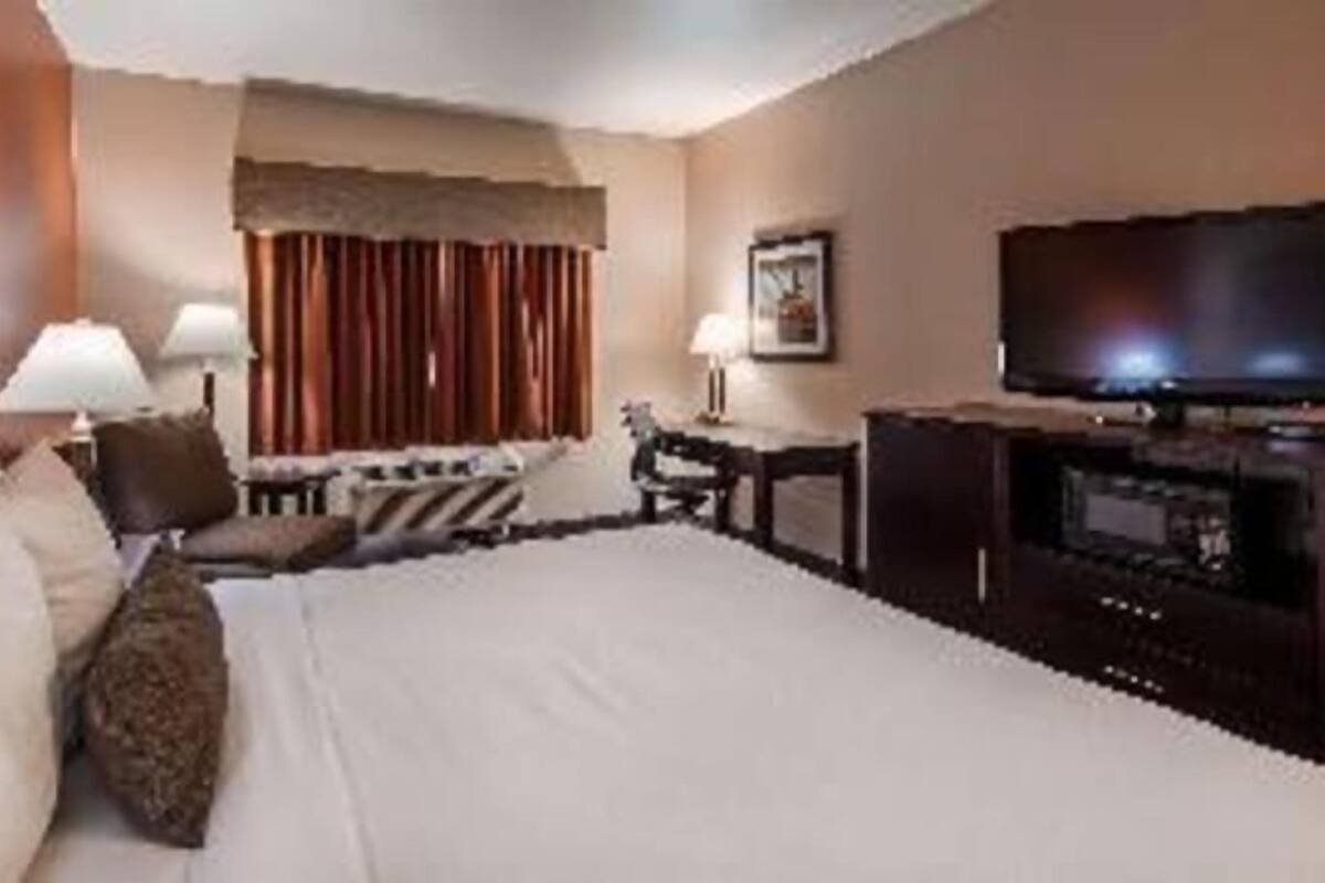 Une chambre d’hôtel avec un grand lit, une télévision, un bureau et une chaise.