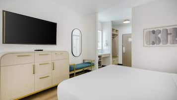 A hotel room with a bed, a TV, a mirror, and a wardrobe.