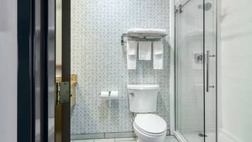 Un baño moderno con inodoro, cabina de ducha y pared con diseño.