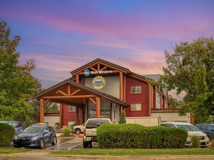 A lodge with a prominent sign, a covered entrance, and a parking lot with several vehicles.