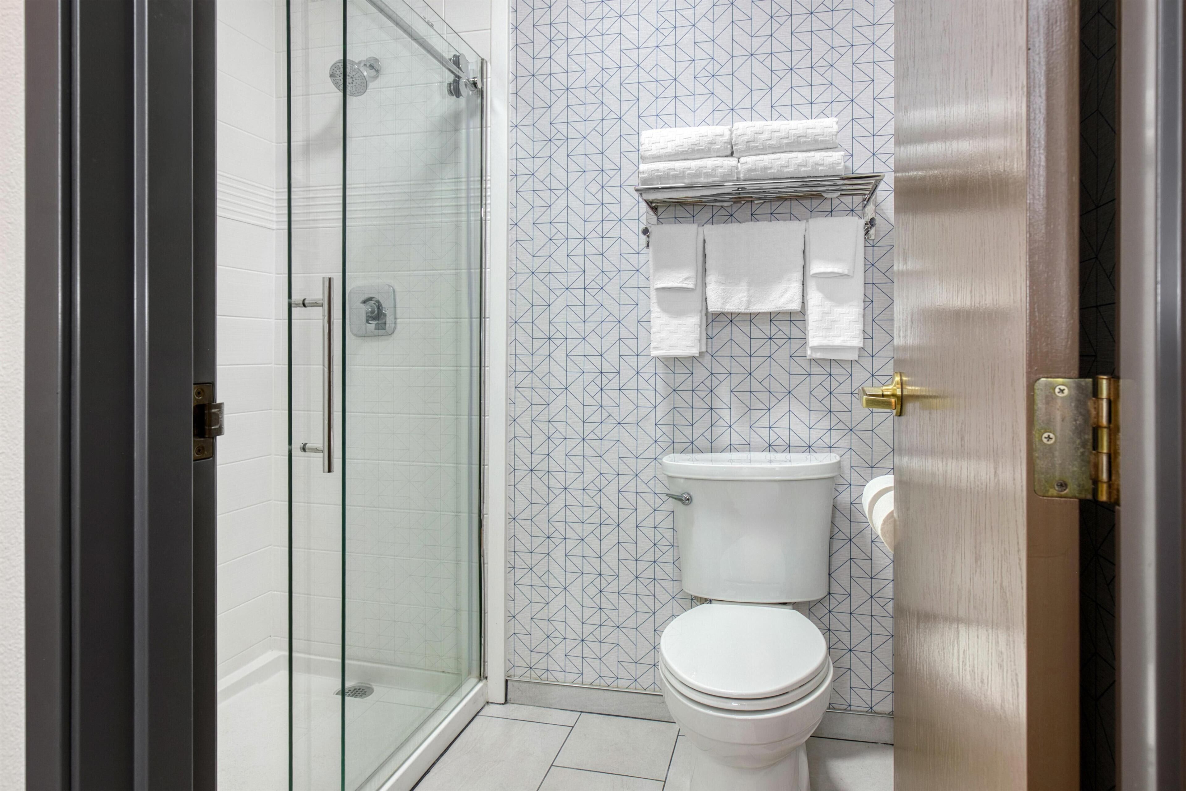 Ein Badezimmer mit Duschkabine, Toilette und Handtuchhalter mit gefalteten Handtüchern.