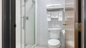 Ein Badezimmer mit Duschkabine, Toilette und Handtuchhalter mit gefalteten Handtüchern.