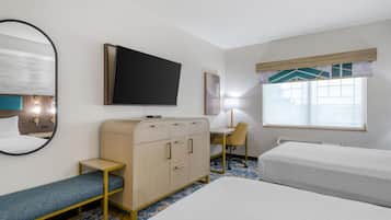 Een hotelkamer met een bed, een bureau, een stoel, een kledingkast, een televisie en een raam met zonwering.
