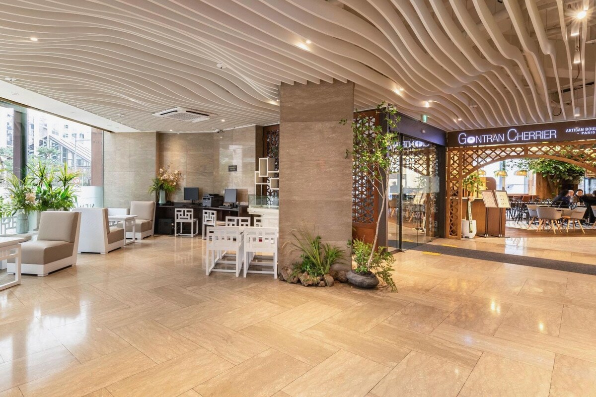 A modern lobby with seating areas, a reception desk, and a restaurant named 'Gontran Cherrier' in the background.