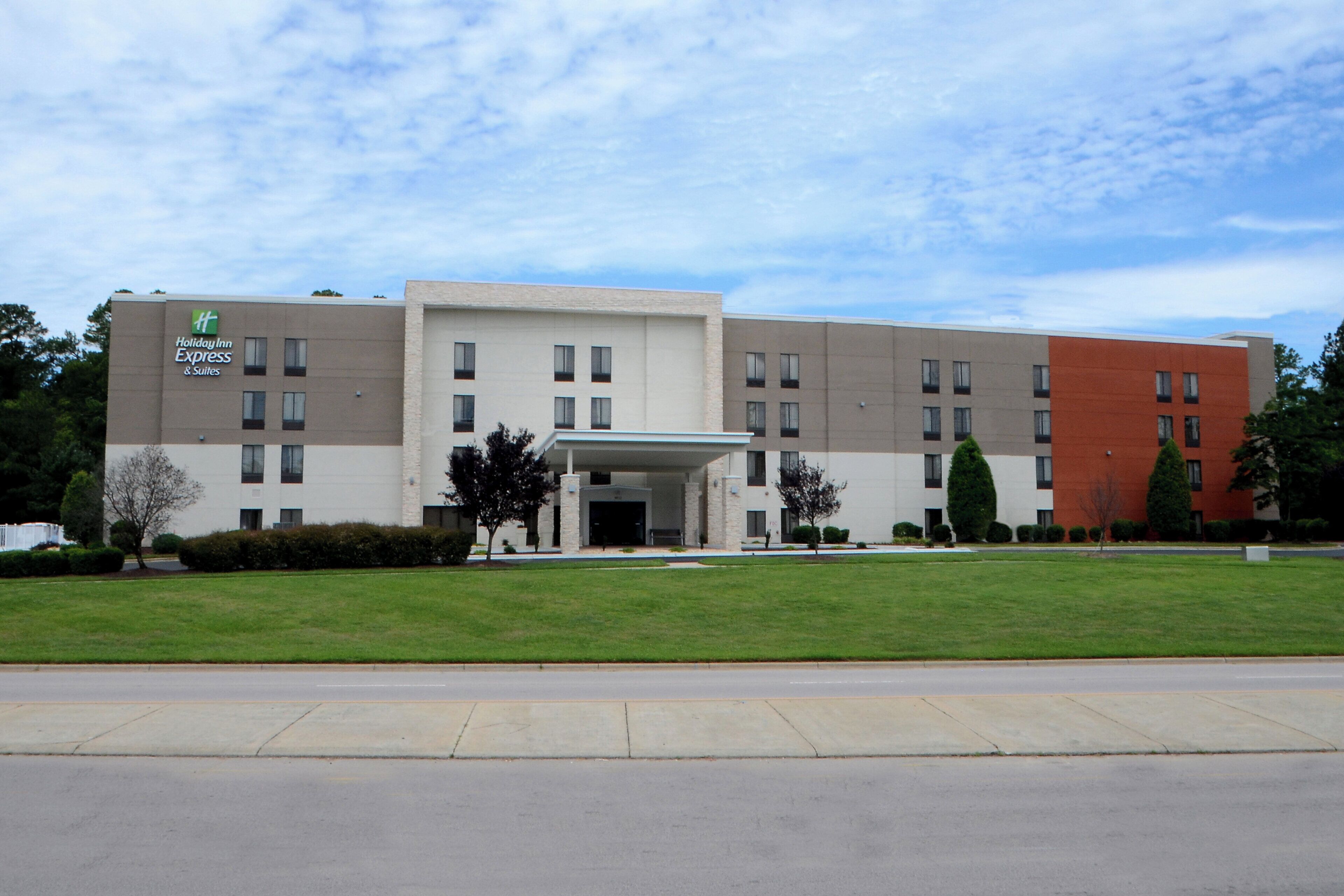 A Holiday Inn Express hotel with a modern design, featuring a flat roof, multiple windows, and a well-maintained lawn in front.