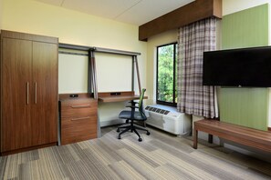 A room with a desk, chair, wardrobe, and a television. - Holiday Inn Express & Suites Raleigh Durham Airport at RTP by IHG (Durham)