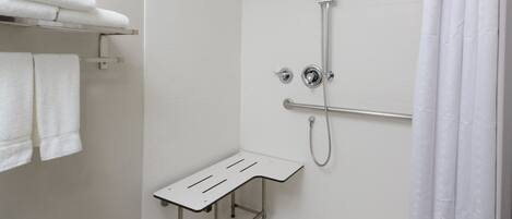 A shower area with a handheld showerhead, a handheld shower attachment, and a shower seat.