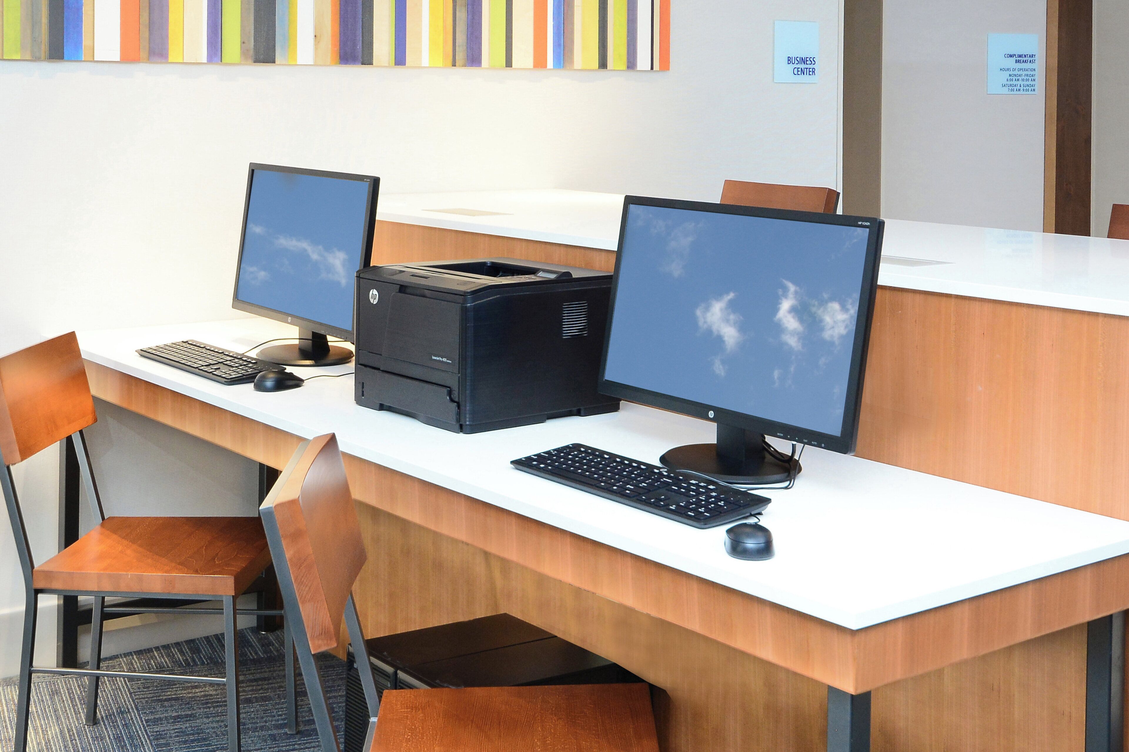 Taulell de recepció amb dos monitors, una impressora i un teclat.