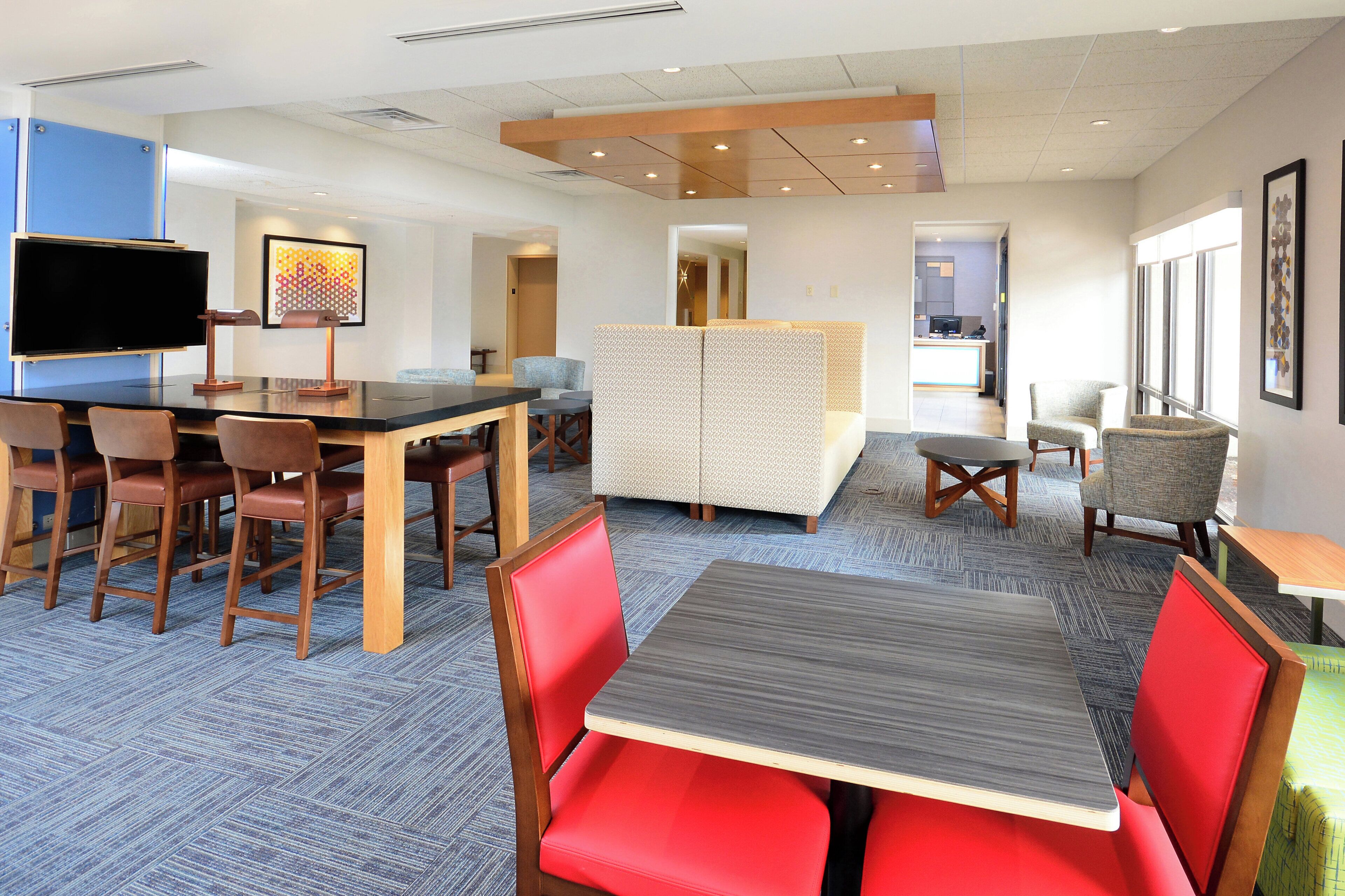 A hotel lobby with a reception desk, seating area, and a television.
