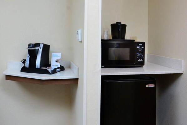 Une petite cuisine équipée d’une machine à café, d’un four à micro-ondes et d’un petit réfrigérateur.