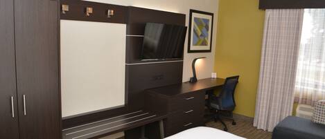 Une chambre d’hôtel comprenant un lit, un bureau avec une chaise, une télévision et une armoire.