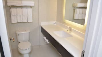 Un baño con inodoro, lavamanos y perchero para toallas.