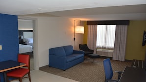 A hotel room with a bed, a blue sofa, a desk with a chair, a small table, and a TV. - Holiday Inn Express & Suites Waterville - North by IHG (Waterville)