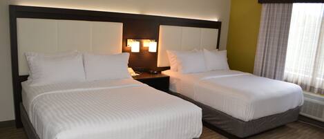 A hotel room with two beds, a nightstand, and a window with curtains.