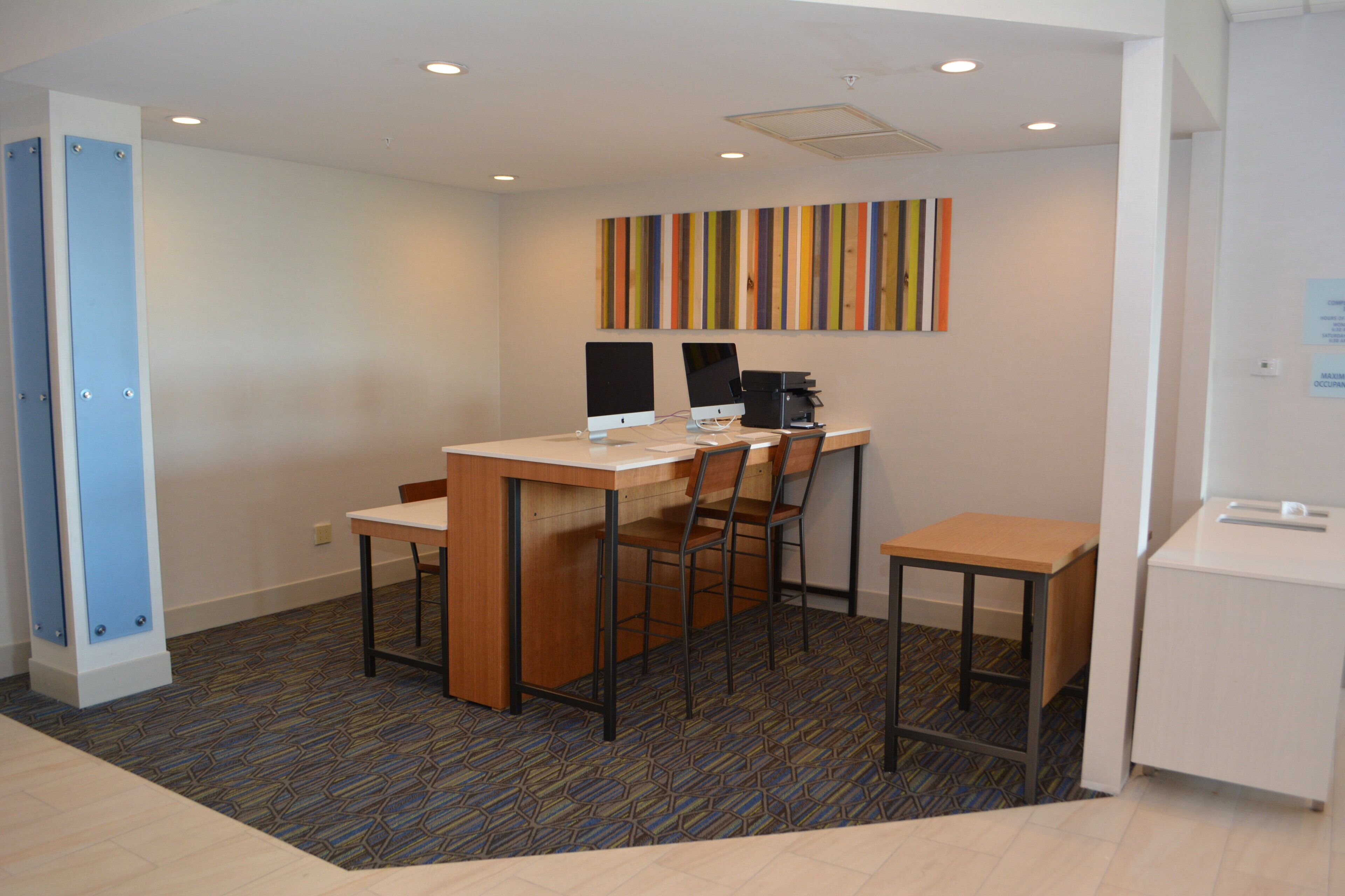 A small office space with a desk, two chairs, a computer, and a printer.