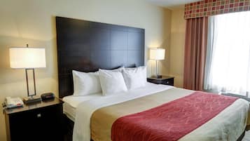 A hotel room with a large bed, two bedside tables, a telephone, and a lamp on each side.