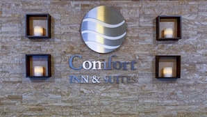 A Comfort Inn & Suites sign with a stylized globe logo and four wall-mounted light fixtures.