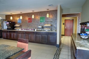 Eine Hotelküche mit einem Buffet, einer Kaffeemaschine und einem Kühlschrank.