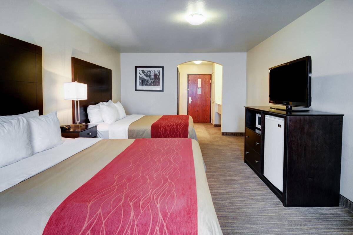 Una habitación de hotel con dos camas, televisión, escritorio y armario.
