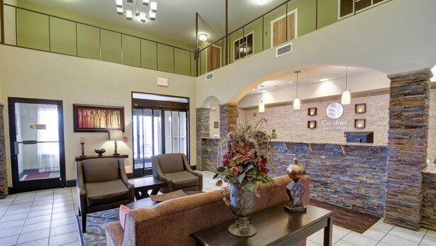 A lobby with a reception desk, seating area, and a stone wall with framed pictures.