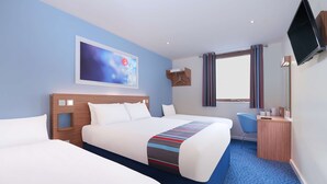 Ein Hotelzimmer mit zwei Betten, einem Schreibtisch, einem Stuhl, einem Fernseher und einem Fenster mit Vorhängen.