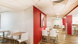 Ein modernes Interieur mit weißen und roten Wänden, Holzboden und einer Mischung aus runden und rechteckigen Tischen mit weißen Stühlen.