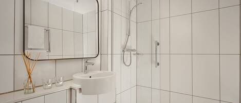 Une salle de bain moderne avec un lavabo blanc, un miroir et une douche.