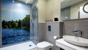 A modern bathroom with a glass-enclosed shower, a toilet, and a sink with a mirror above.