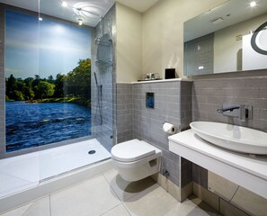 A modern bathroom with a glass-enclosed shower, a toilet, and a sink with a mirror above.