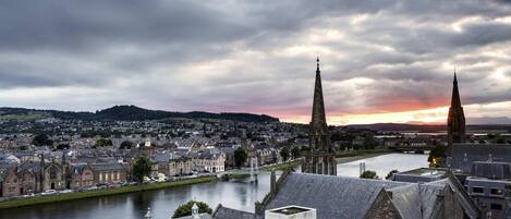 A historic town with a river, two prominent church spires, and a bridge.