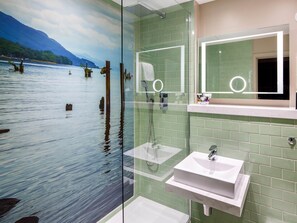 A bathroom with a glass partition, a sink, and a mirror.