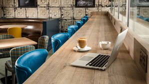 A modern cafe with a wooden counter, blue leather chairs, and a laptop. - Mercure Inverness Hotel (Inverness)