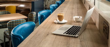 A modern cafe with a wooden counter, blue leather chairs, and a laptop.